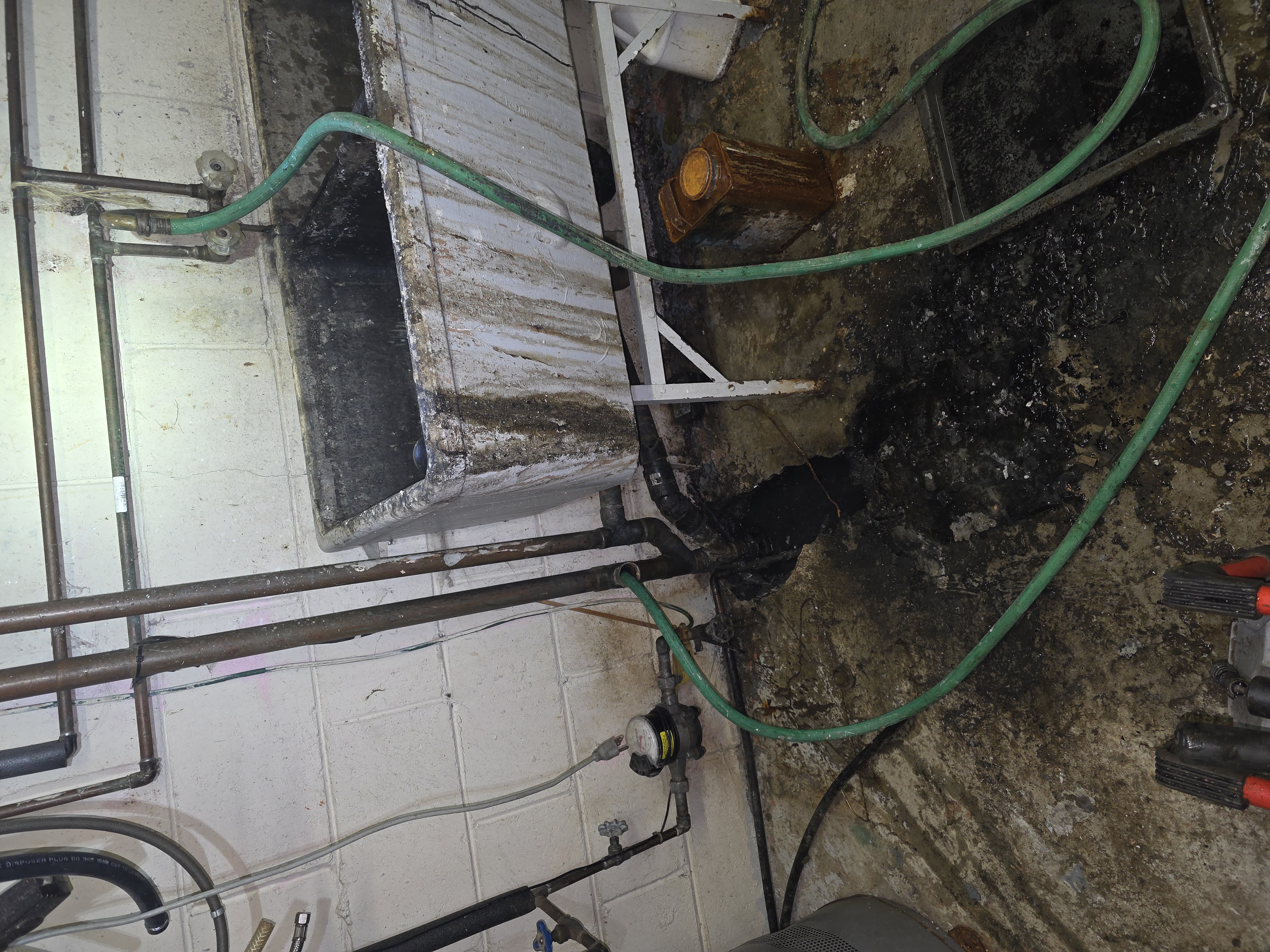 Using a K60 plumbing snaking machine to clear a clogged laundry sink drain line.